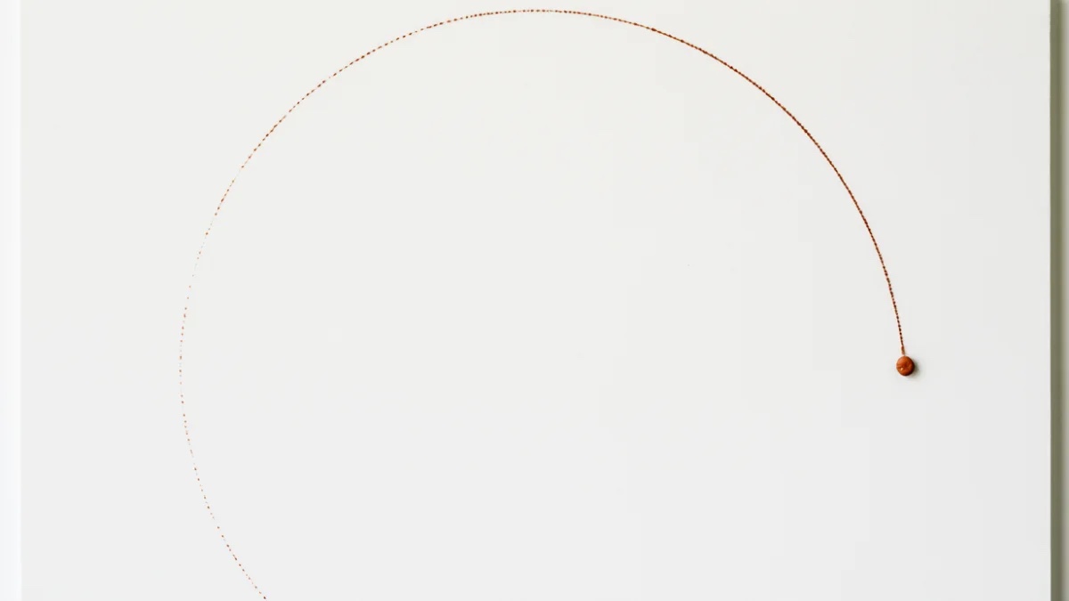 Arco punteado terracota que termina en una pequeña esfera sobre papel blanco